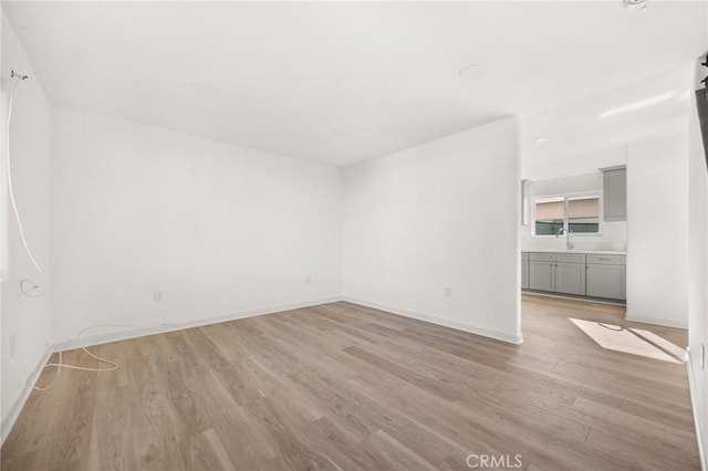 unfurnished room featuring light wood-type flooring and sink