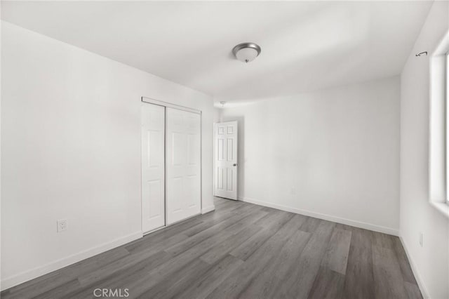 unfurnished bedroom featuring a closet and dark wood-type flooring