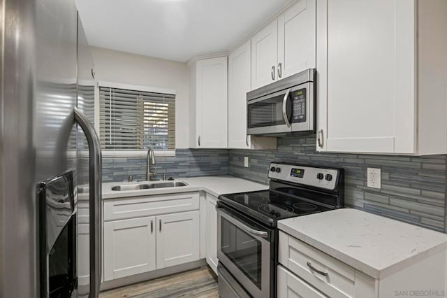 kitchen with light stone countertops, white cabinetry, sink, and appliances with stainless steel finishes