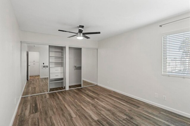 unfurnished bedroom featuring multiple closets, ceiling fan, and dark wood-type flooring