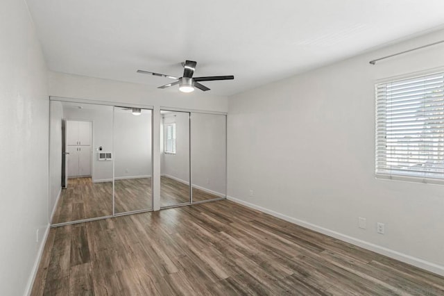 unfurnished bedroom featuring two closets, dark hardwood / wood-style floors, and ceiling fan