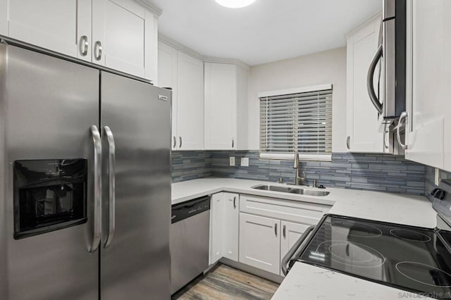 kitchen with backsplash, sink, light wood-type flooring, appliances with stainless steel finishes, and white cabinetry