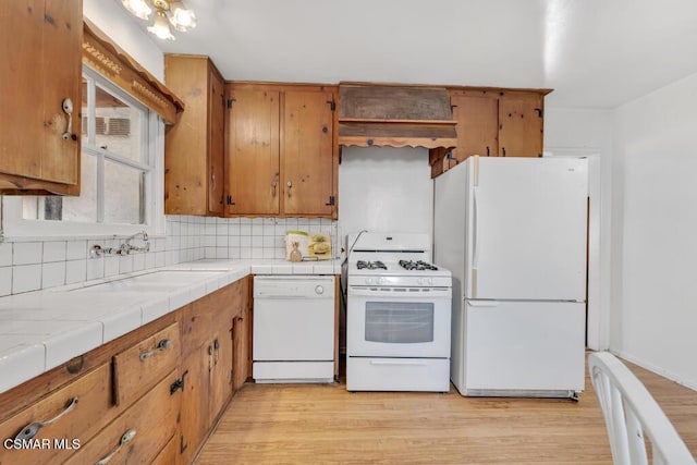 kitchen featuring white appliances, sink, decorative backsplash, tile counters, and light hardwood / wood-style floors