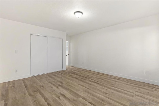 unfurnished bedroom featuring light hardwood / wood-style flooring and a closet