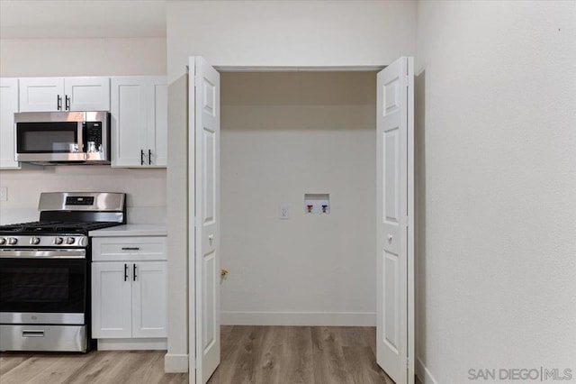 kitchen featuring white cabinetry, appliances with stainless steel finishes, and light hardwood / wood-style flooring