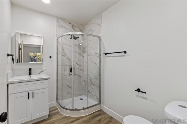 bathroom featuring vanity, wood-type flooring, a shower with shower door, and toilet