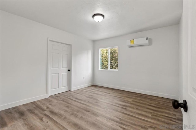 empty room with a wall unit AC and hardwood / wood-style floors