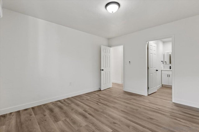 unfurnished bedroom featuring ensuite bathroom and light hardwood / wood-style floors