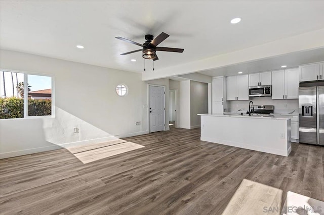 kitchen with ceiling fan, stainless steel appliances, a center island with sink, white cabinets, and light wood-type flooring