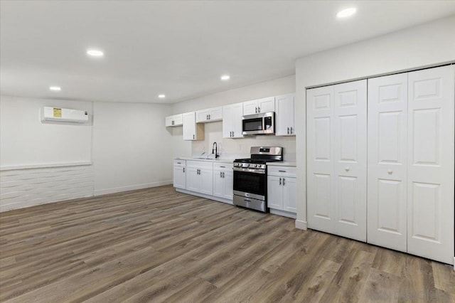 kitchen featuring dark hardwood / wood-style flooring, a wall unit AC, white cabinetry, and appliances with stainless steel finishes