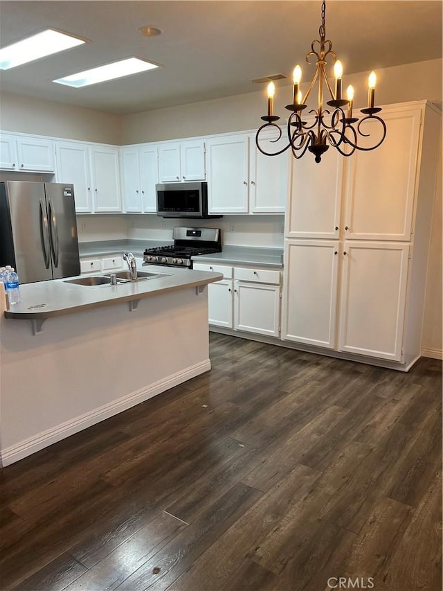 kitchen with pendant lighting, sink, dark wood-type flooring, appliances with stainless steel finishes, and white cabinetry