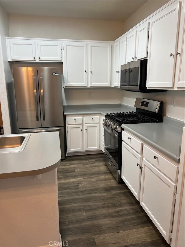 kitchen featuring stainless steel appliances, sink, dark wood-type flooring, and white cabinets