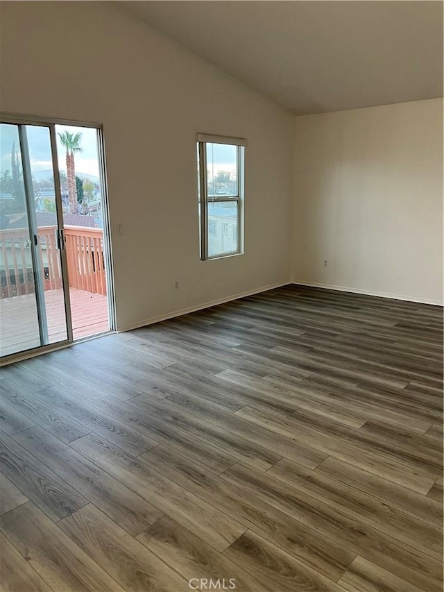 spare room with vaulted ceiling and dark hardwood / wood-style flooring