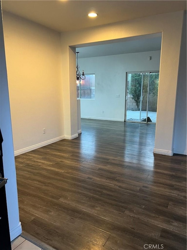 unfurnished room featuring dark hardwood / wood-style flooring and a notable chandelier