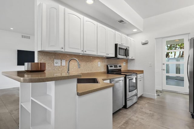 kitchen with white cabinets, sink, decorative backsplash, kitchen peninsula, and stainless steel appliances