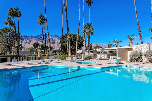 view of swimming pool with a mountain view, a patio area, and a community hot tub