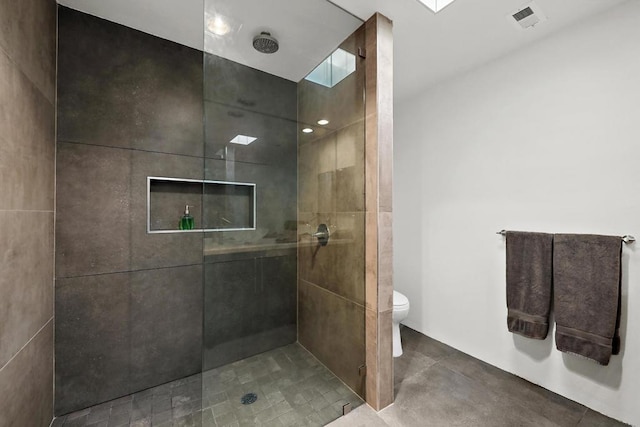 bathroom with a tile shower and toilet