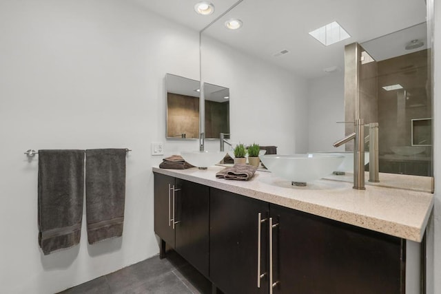 bathroom featuring a skylight, tile patterned flooring, vanity, and walk in shower