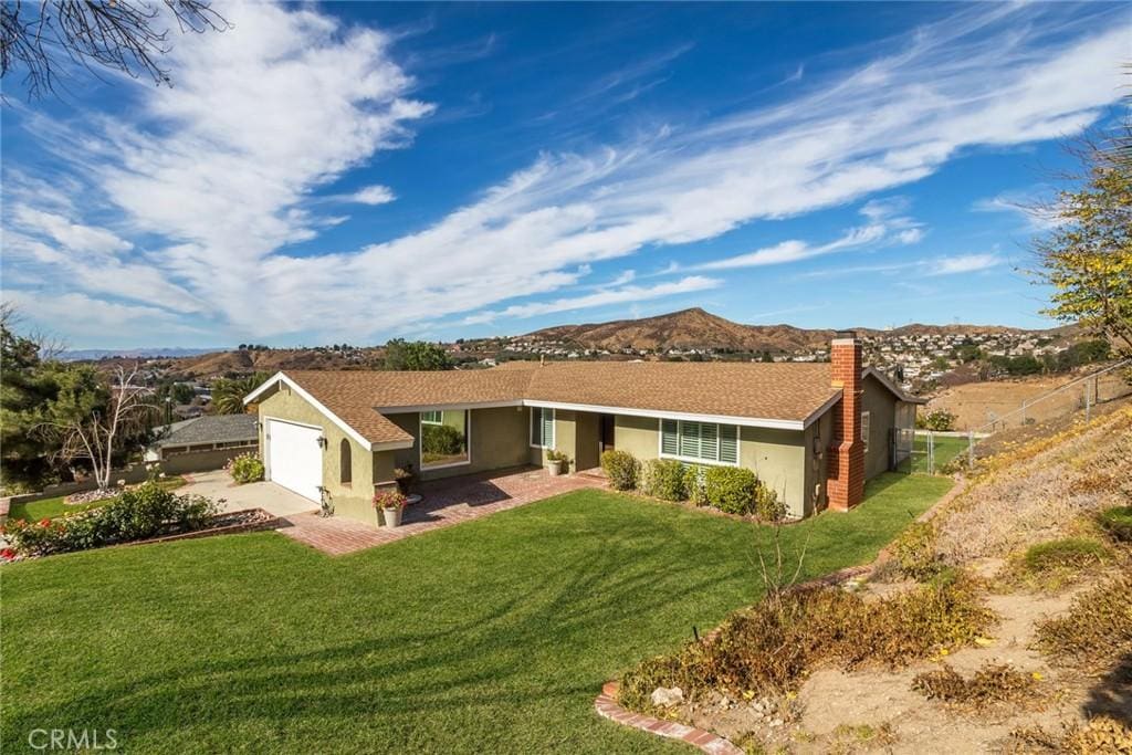 single story home featuring a mountain view, a front lawn, and a garage