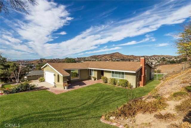 single story home featuring a mountain view, a front lawn, and a garage