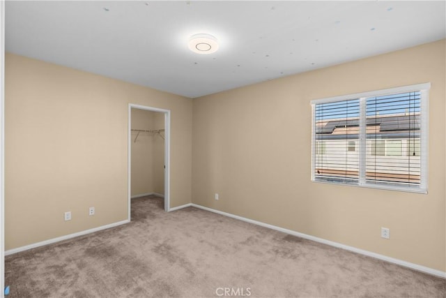 unfurnished bedroom featuring light carpet, a walk in closet, and a closet