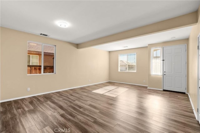 spare room with beam ceiling and dark hardwood / wood-style floors