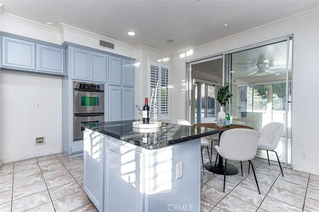 kitchen with dark stone countertops, ceiling fan, crown molding, and stainless steel double oven