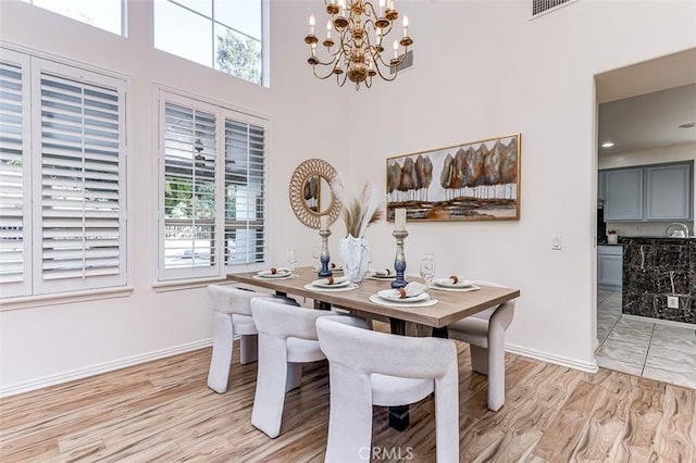 dining space with light wood-type flooring, a wealth of natural light, and an inviting chandelier