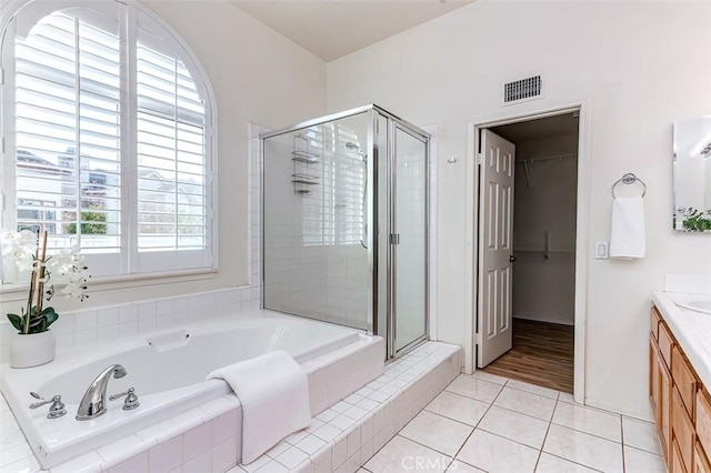 bathroom with tile patterned flooring, vanity, and plus walk in shower