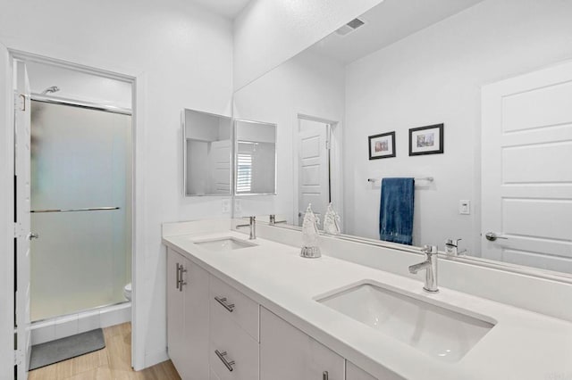 bathroom featuring vanity, toilet, a shower with door, and wood-type flooring