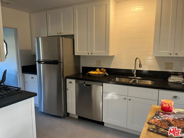 kitchen with white cabinets, decorative backsplash, stainless steel appliances, and sink