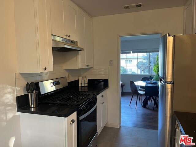 kitchen with dark tile patterned flooring, stainless steel appliances, and white cabinetry