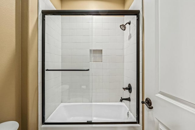 bathroom with shower / bath combination with glass door and toilet