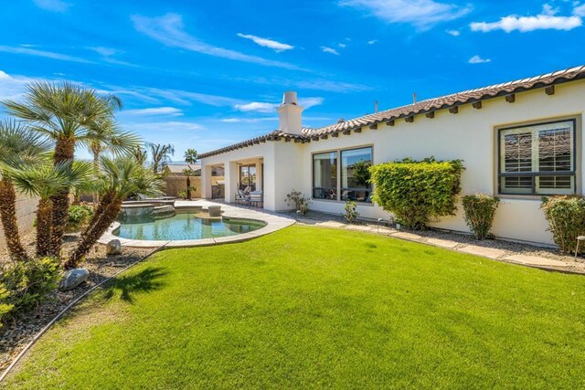 back of property with a yard, a patio area, and a pool with hot tub