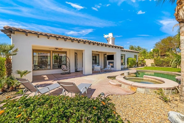 back of house featuring ceiling fan, an in ground hot tub, and a patio