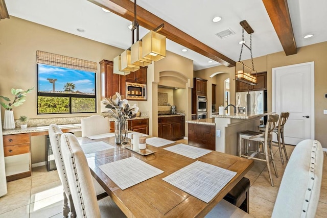 tiled dining area featuring beamed ceiling