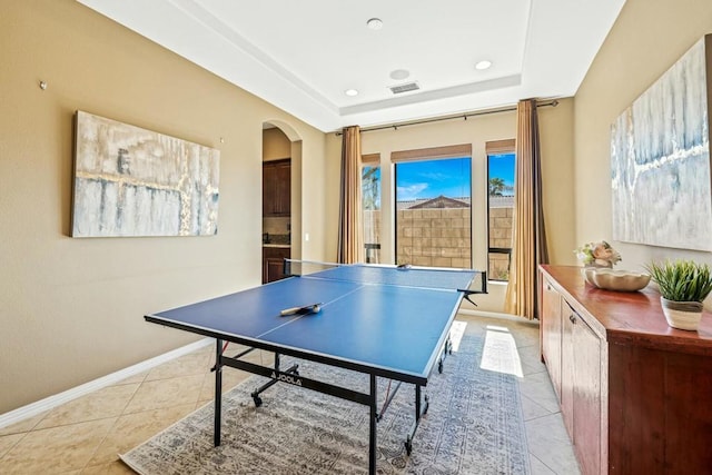 game room with light tile patterned floors, a tray ceiling, and a wealth of natural light