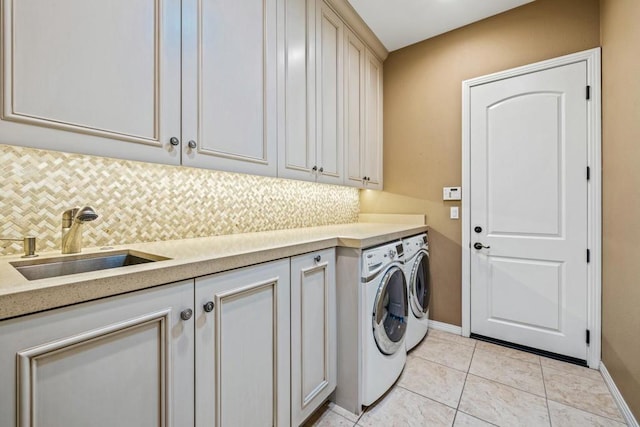 washroom with washing machine and clothes dryer, light tile patterned floors, cabinets, and sink