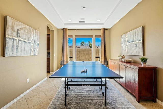 rec room with a tray ceiling and light tile patterned flooring