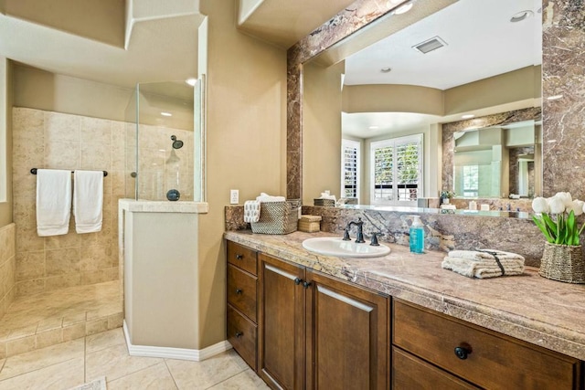 bathroom featuring a tile shower, vanity, and tile patterned floors