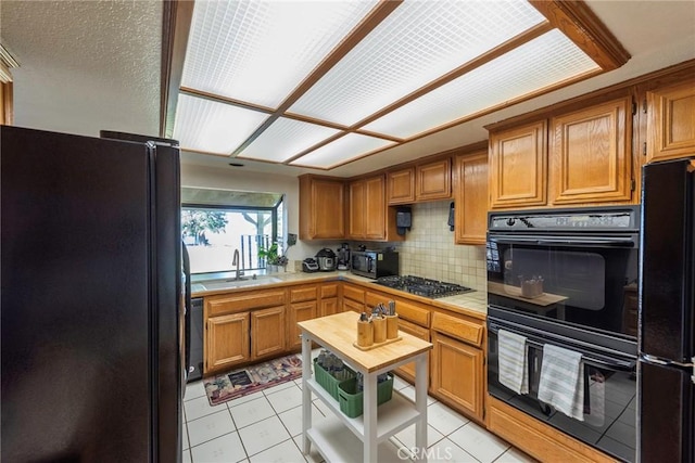 kitchen featuring decorative backsplash, light tile patterned floors, sink, and black appliances