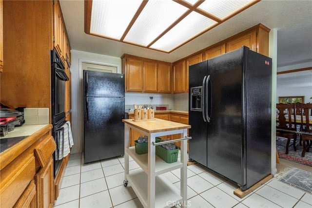 kitchen featuring black appliances, light tile patterned floors, and tile countertops