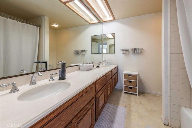 bathroom with a skylight, a shower with curtain, double vanity, a sink, and tile patterned flooring