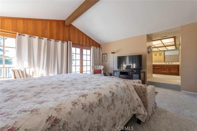 bedroom with lofted ceiling with beams, connected bathroom, wooden walls, light carpet, and a sink