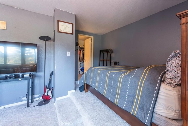 bedroom featuring carpet floors, a spacious closet, and baseboards