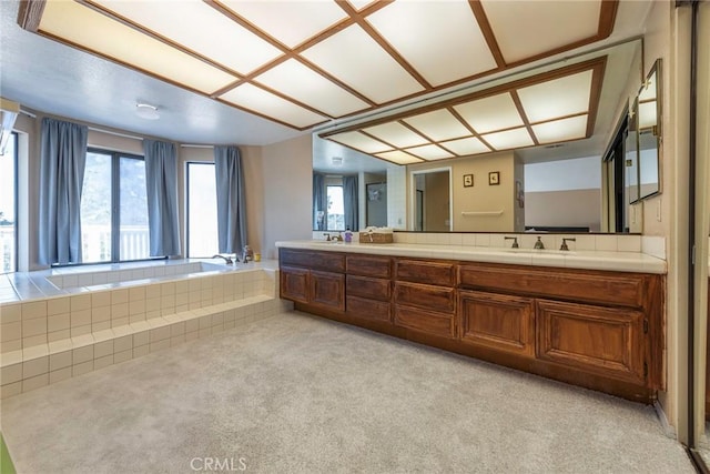 bathroom with double vanity, a sink, and a bath