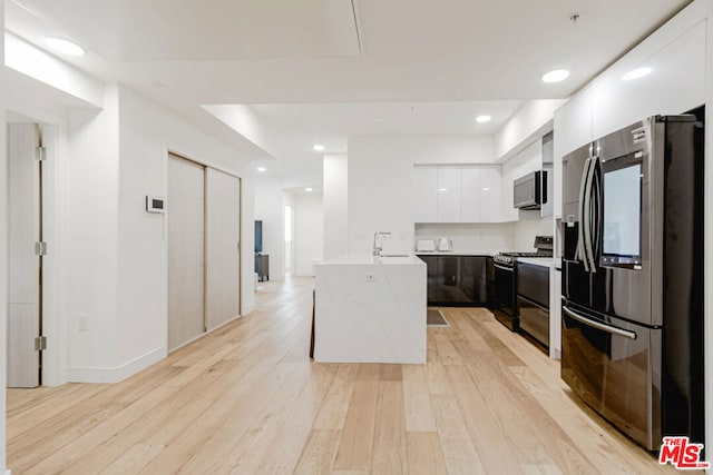 kitchen with white cabinets, a center island, stainless steel appliances, and light hardwood / wood-style flooring