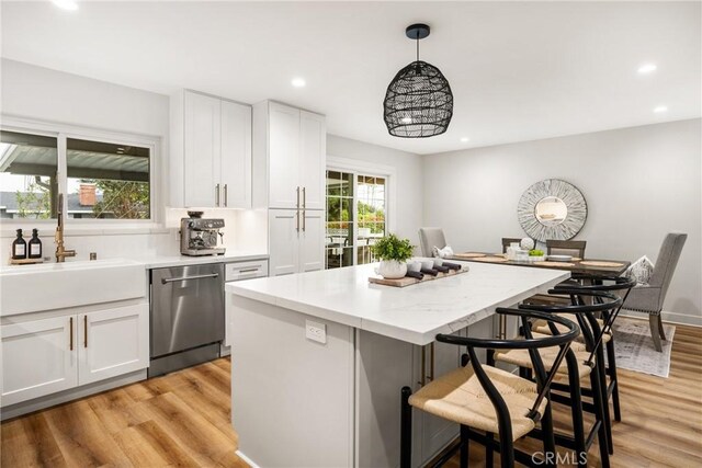 kitchen featuring white cabinets, dishwasher, a kitchen bar, and decorative light fixtures