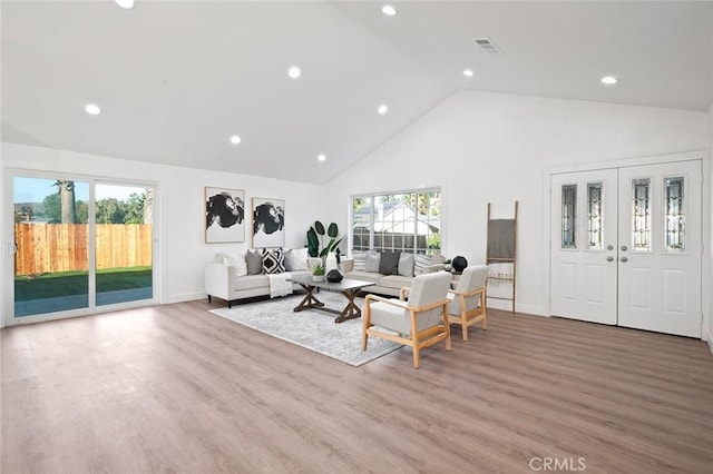 living room featuring high vaulted ceiling, light hardwood / wood-style floors, and a wealth of natural light