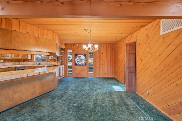 kitchen featuring dark colored carpet, tile counters, decorative light fixtures, oven, and beamed ceiling